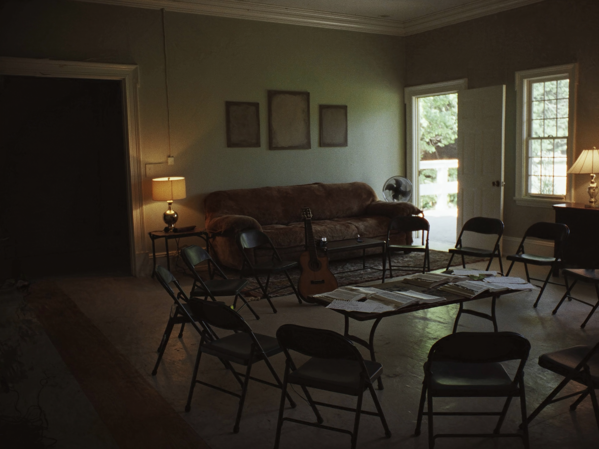 A youth room with a circle of chairs, a guitar on a stand and open Bibles on a low table
