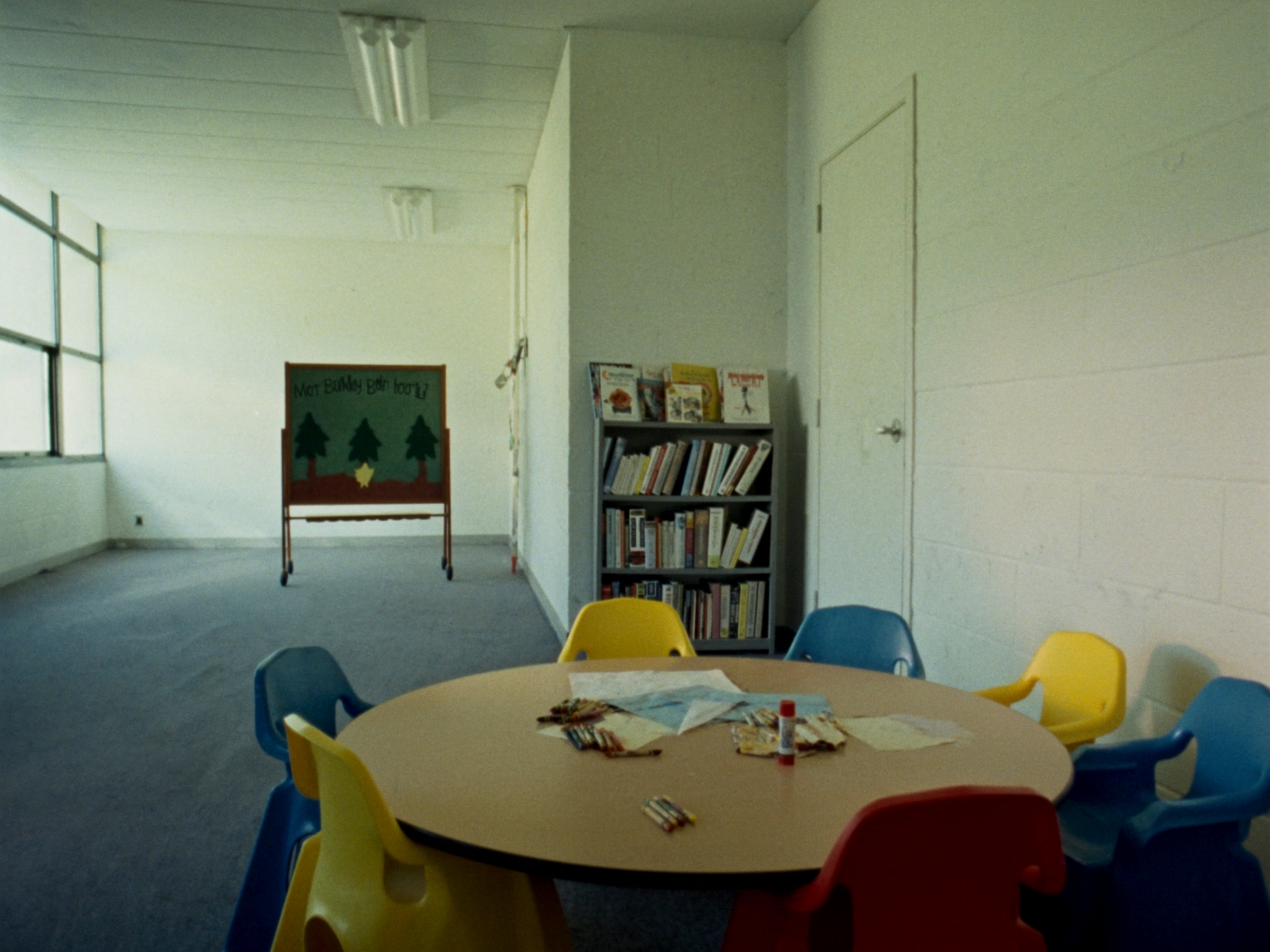 A children's classroom set up with a low craft table, small chairs and picture Bibles