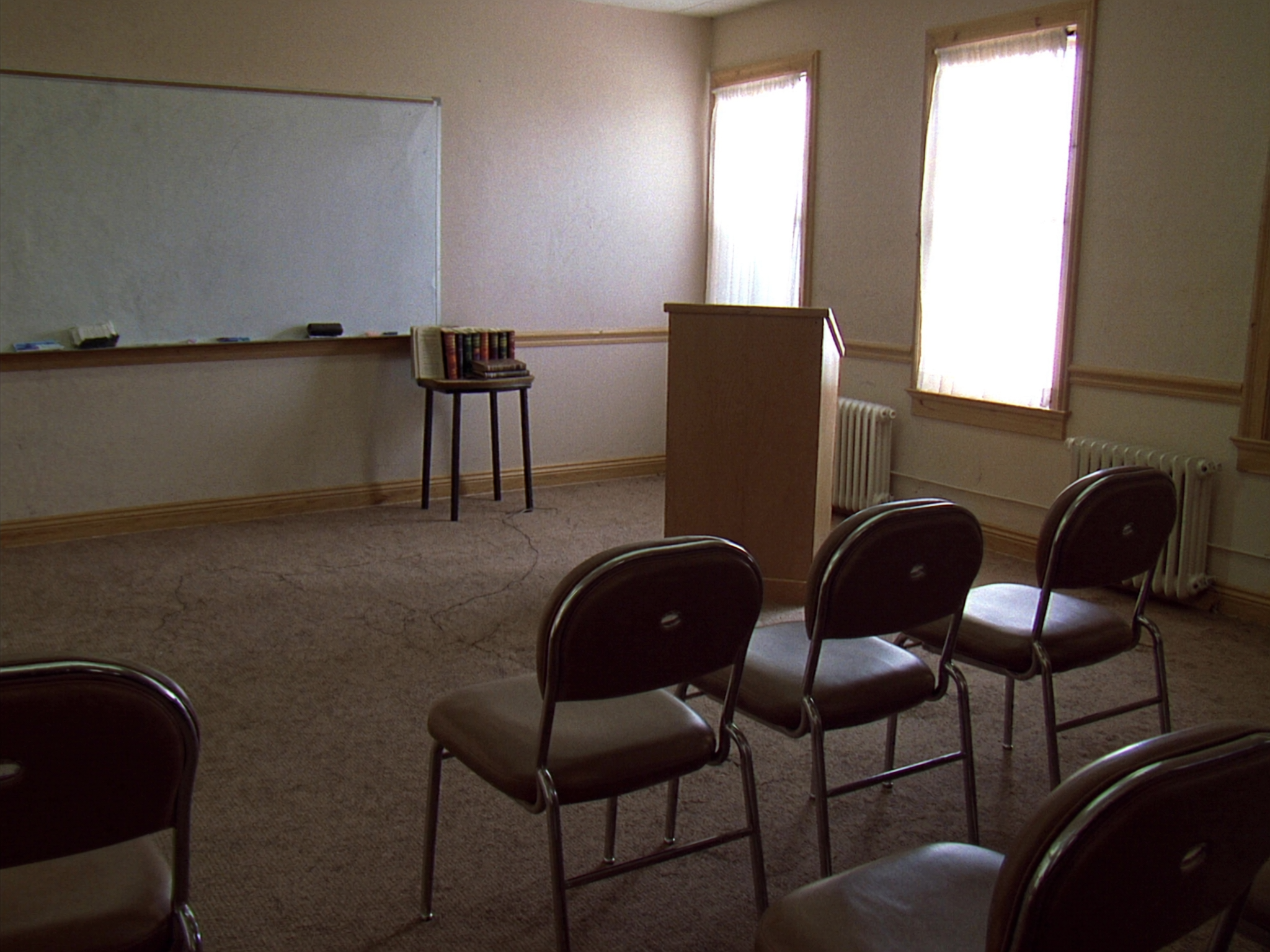 An adult Sunday school classroom with rows of chairs facing a simple wooden lectern