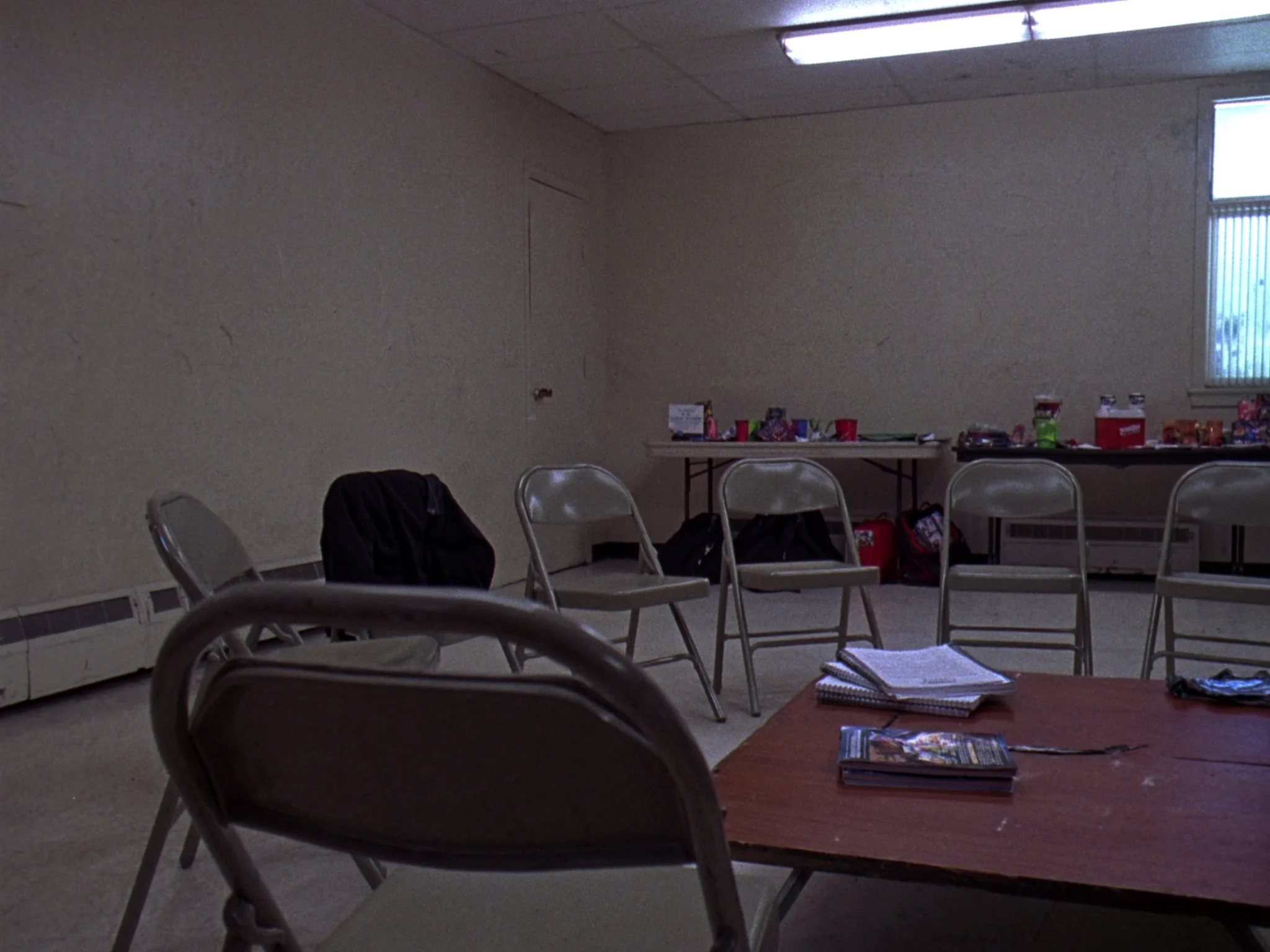 Folding chairs pulled into a semicircle in a middle school youth room with study guides on the table